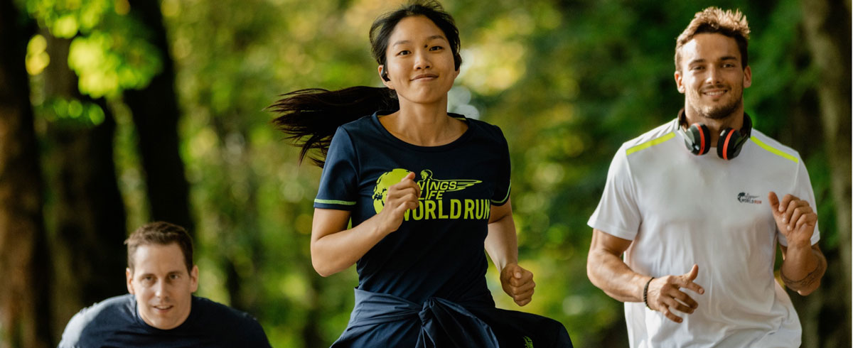 Tri učesnika globalne trke „Wings for life“ radosno trče dok nose Philips sportske slušalice.